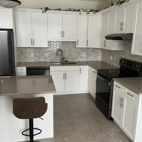 A refaced Nanaimo kitchen with white shaker doors, stone counters and a breakfast bar