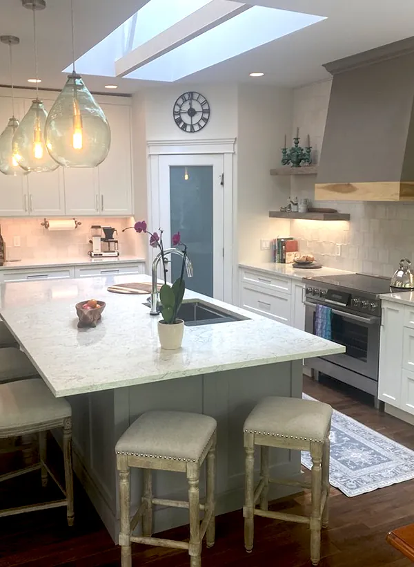 A high-end Nanaimo kitchen with a skylight, quartz island and counters, and a custom range hood