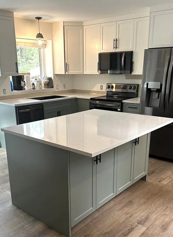 A newly completed full custom Nanaimo kitchen with sage-green island cabinets and black stainless appliances