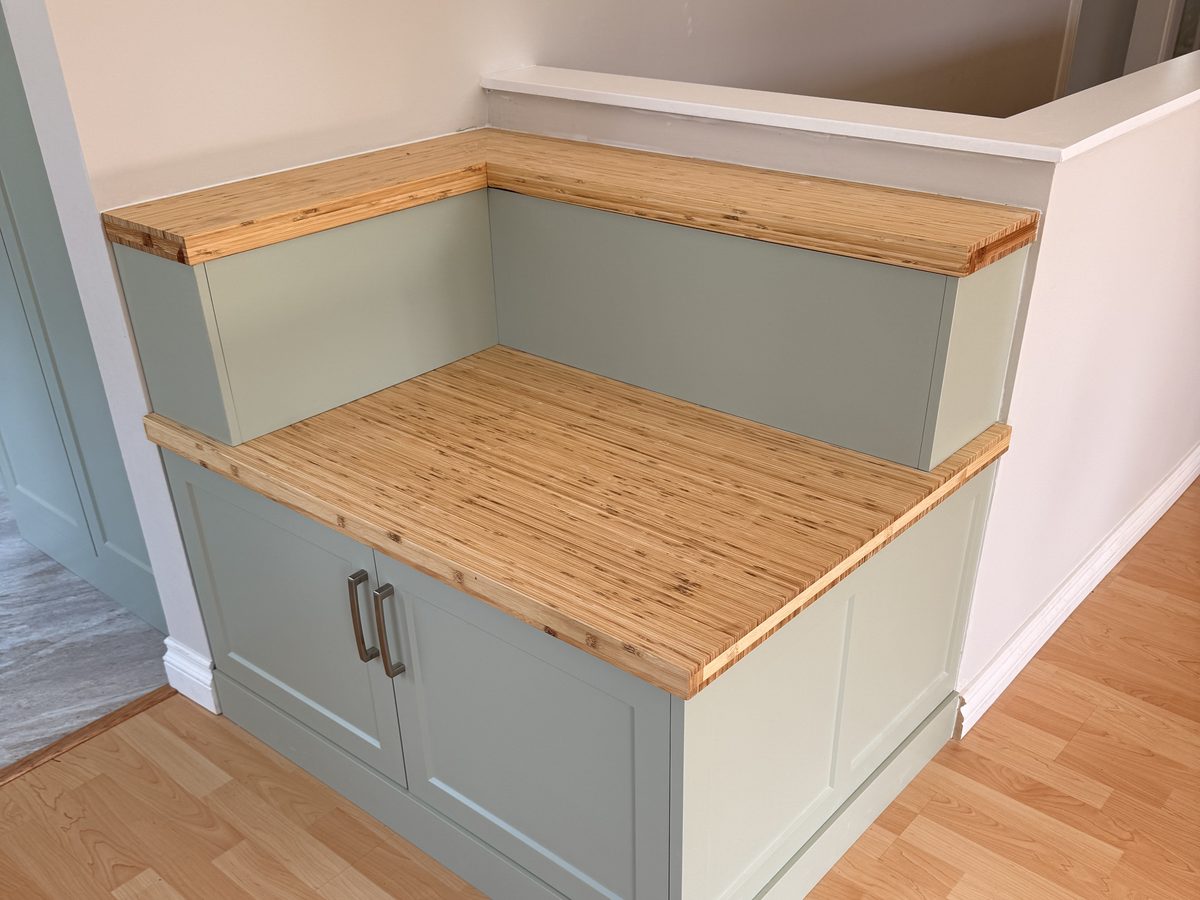 The Ready to Sell kitchen in Nanaimo — a sage-green corner storage bench with a bamboo edge-grain seat, built where the old pantry bank stood