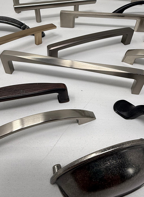 A spread of cabinet handle samples in brushed nickel, matte black, bronze and brass