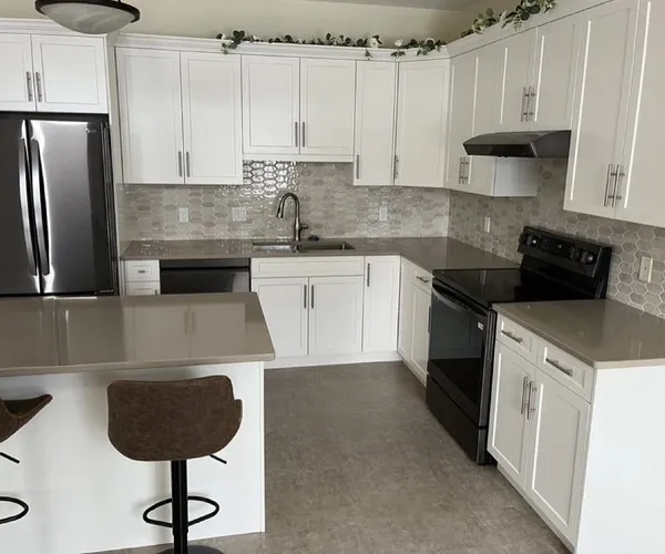 A refaced Nanaimo kitchen with white shaker doors, stone counters and a breakfast bar