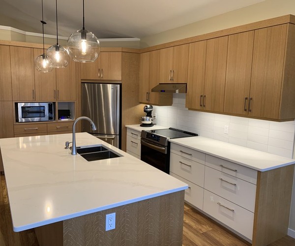 A full custom Nanaimo kitchen in rift-cut oak with a large quartz island and glass pendant lights