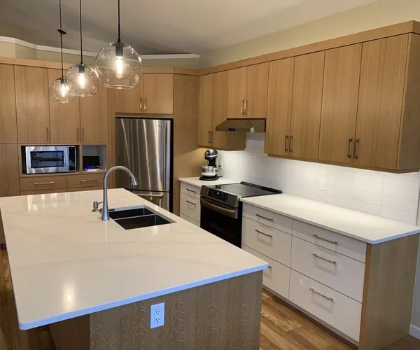 A full custom Nanaimo kitchen in rift-cut oak with a large quartz island and glass pendant lights