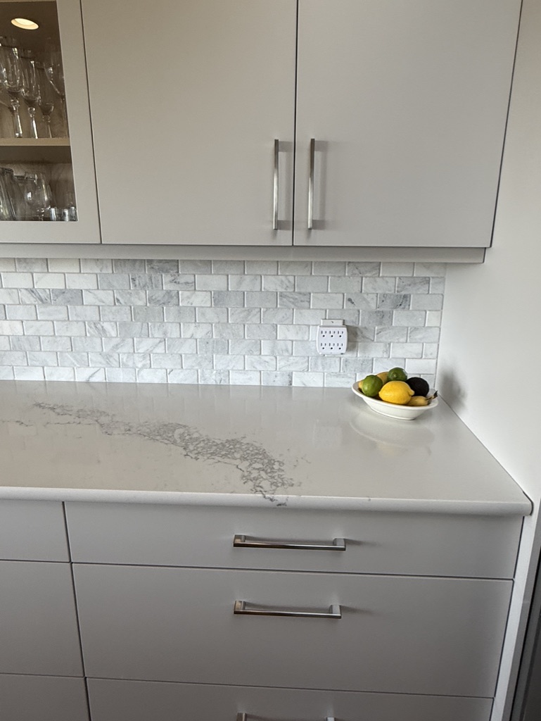 Quartz countertop and marble subway tile backsplash kept in the renovation.
