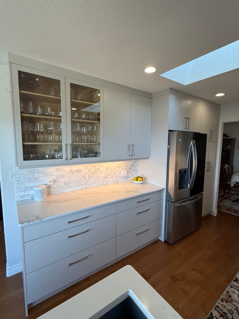Glass-insert upper cabinets above deep drawers in the finished kitchen.