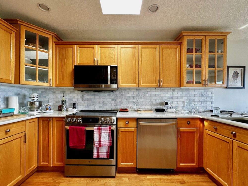 A Nanaimo kitchen before its partial renovation, in honey-oak raised-panel doors, with the upper cabinets stopping short of the ceiling