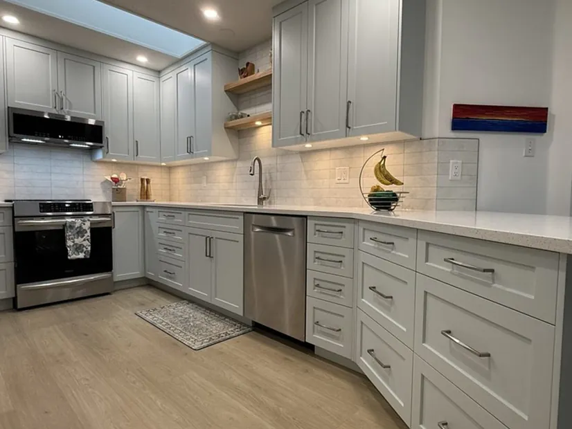 A pale grey shaker kitchen with a skylight, open wood shelving and a tile backsplash